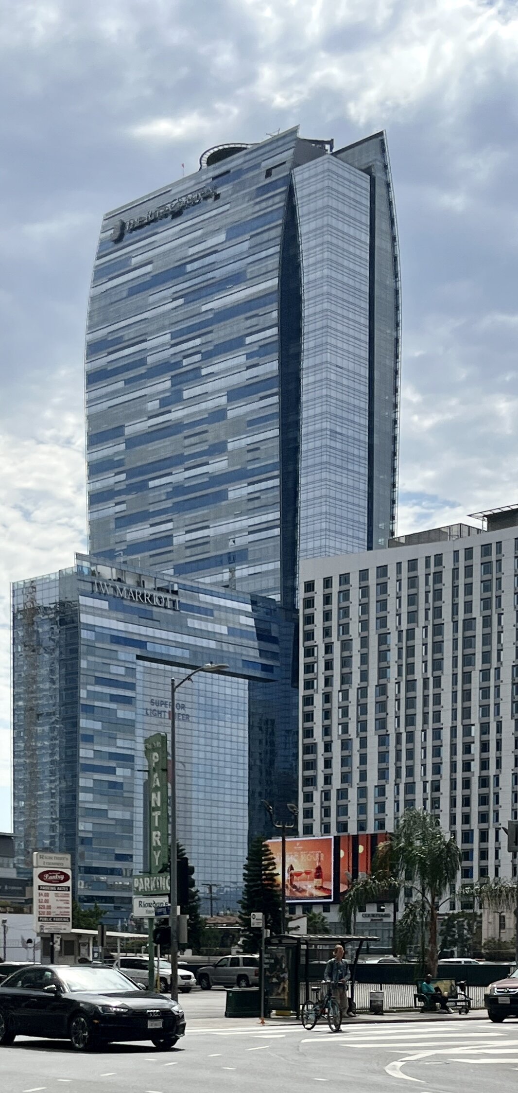 Tall glass hotel tower of the Ritz-Carlton and JW Marriott in downtown Los Angeles under a cloudy sky