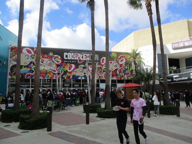Fans lining up under a Takashi Murakami flower mural banner at a past ComplexCon entrance
