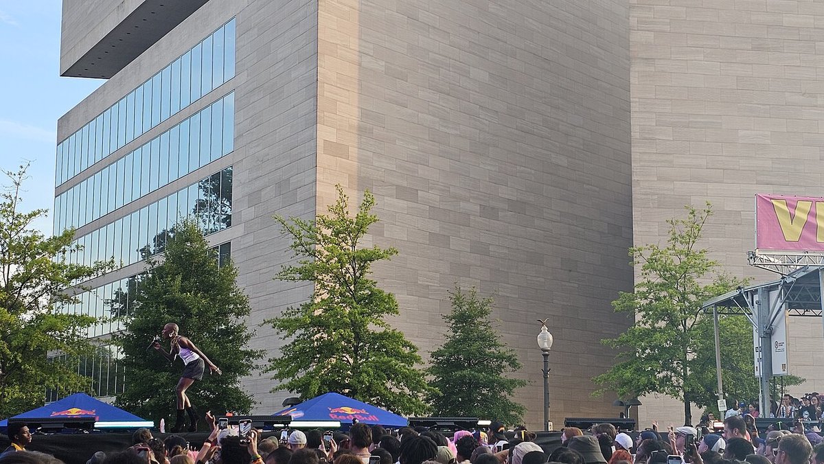 Cynthia Erivo singing into a microphone on an outdoor stage