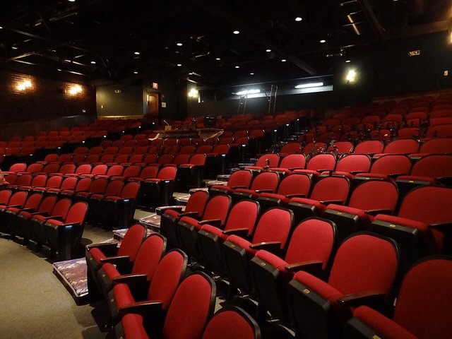 Rows of red theatre seats in a dark auditorium