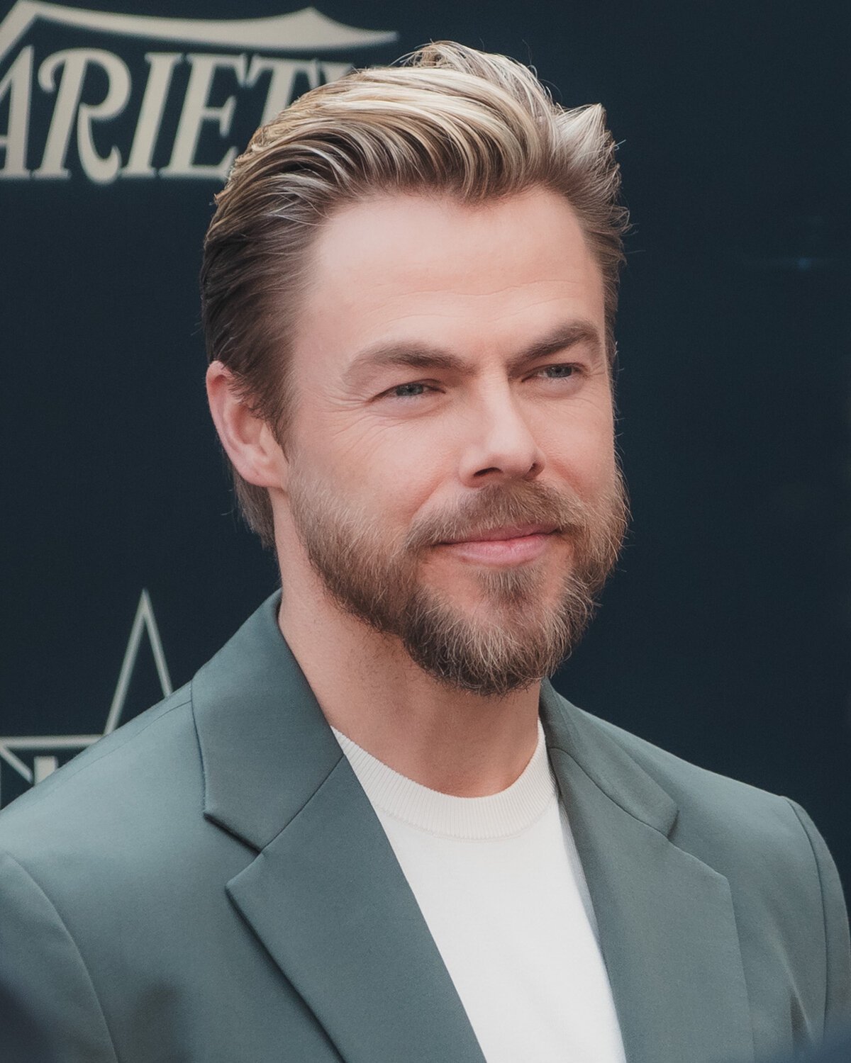 Portrait of Derek Hough in a green blazer and white shirt