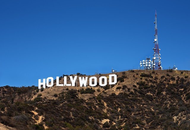 White Hollywood Sign letters on a brown hillside under a clear blue sky