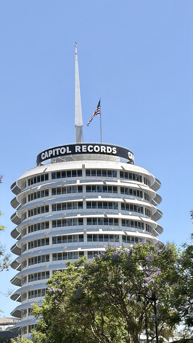 The round white Capitol Records Tower in Hollywood against a clear blue sky, with an American flag on top