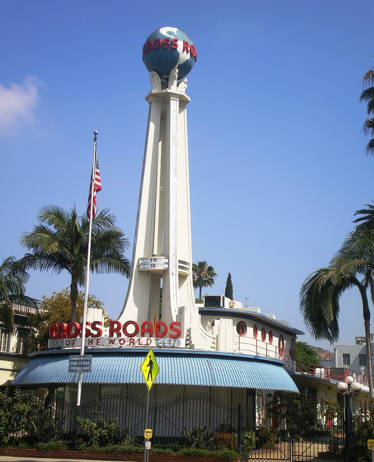 White Art Deco tower topped with a globe and red neon Cross Roads of the World lettering in Hollywood