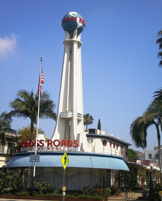 White Art Deco tower topped with a globe and red neon Cross Roads of the World lettering in Hollywood