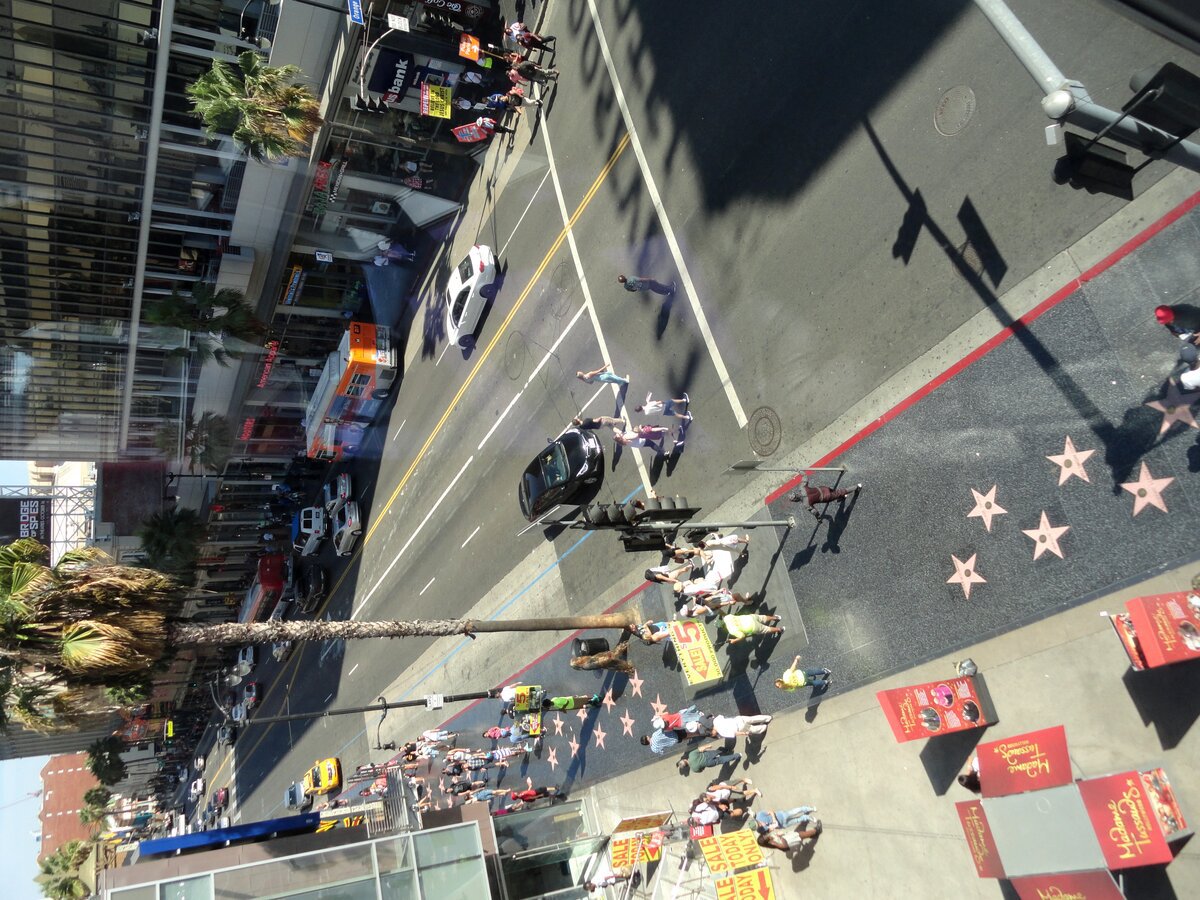 Hollywood Boulevard seen from above, with Walk of Fame stars on the sidewalk, buses and pedestrians crossing the street