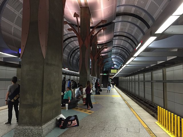 Metro B Line platform at Hollywood/Highland with a curved perforated ceiling and a few waiting riders