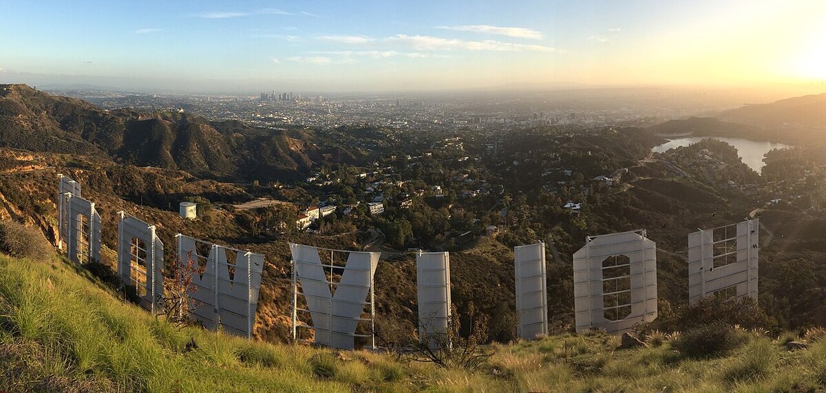 View from behind the Hollywood Sign letters at sunset, looking over the hills toward the Los Angeles skyline