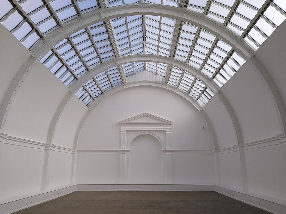 A bright, arched gallery hall with a glass skylight ceiling