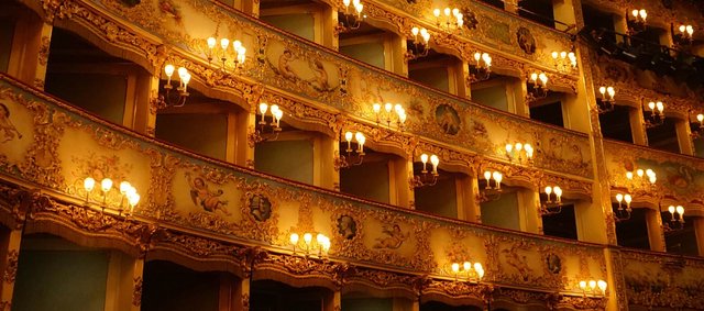 Tiers of gilded Italian opera house boxes lit by rows of warm lamps, like the Milan theatres this Nabucco production is set in