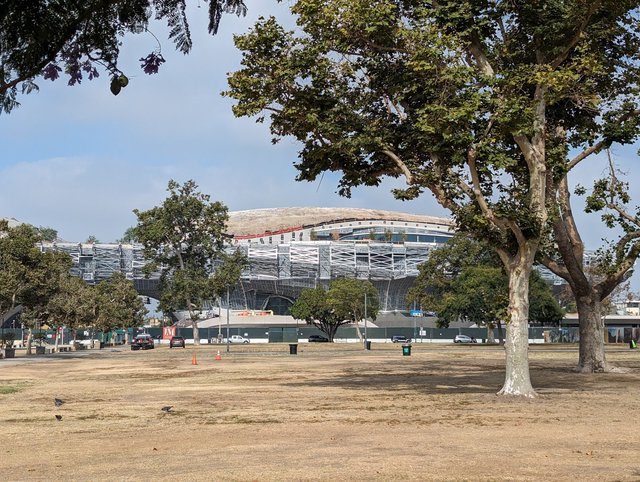 Lucas Museum of Narrative Art building exterior under construction in Exposition Park, Los Angeles, showing its distinctive cloud-like curved FRP facade