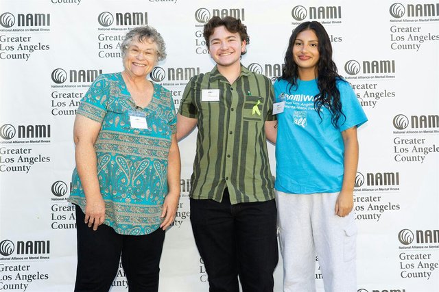 Three smiling attendees posing in front of a NAMI Greater Los Angeles County banner