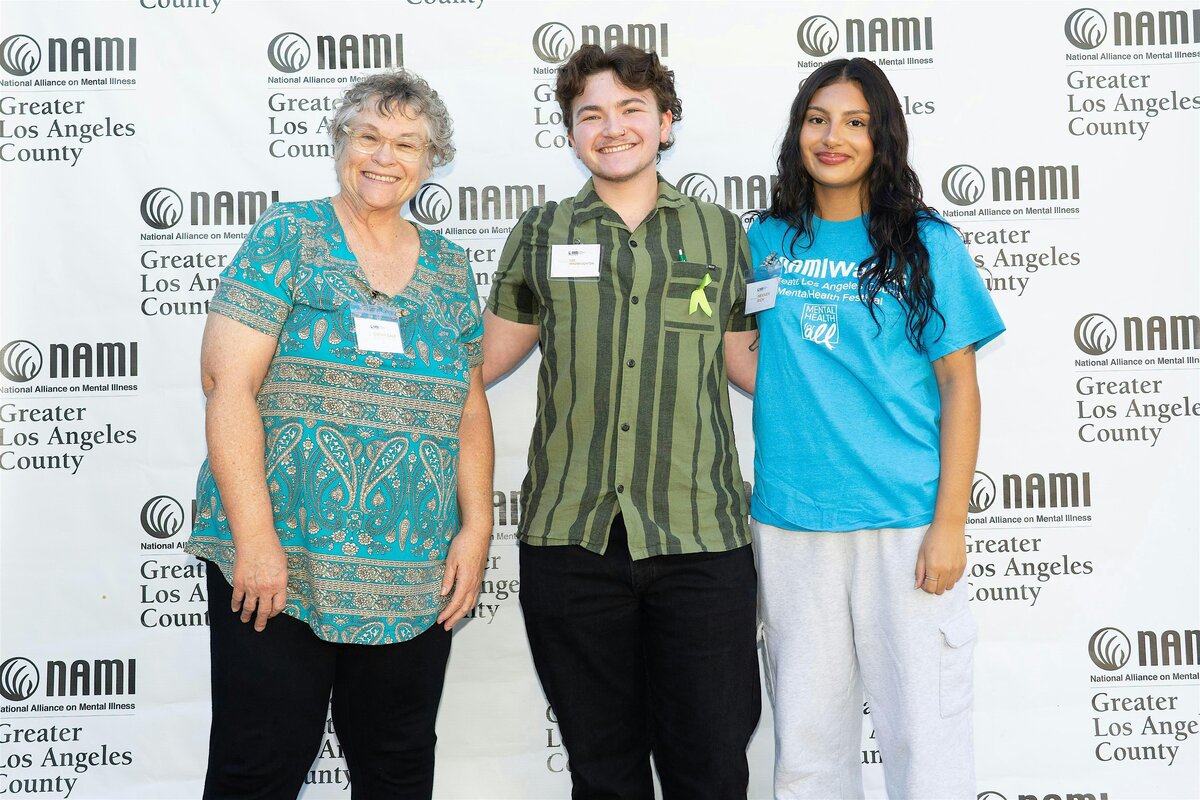 Three smiling attendees posing in front of a NAMI Greater Los Angeles County banner
