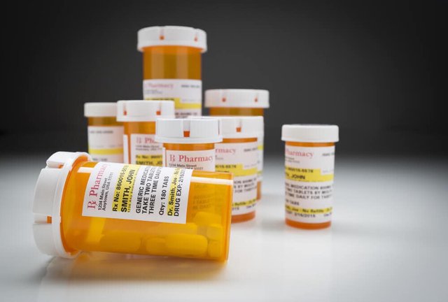 Several orange prescription pill bottles with pharmacy labels on a white surface