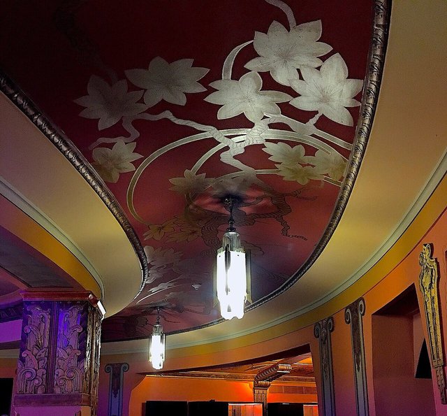 Painted floral ceiling and glowing Art Deco pendant lights in a lobby of The Wiltern