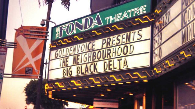 The Fonda Theatre's lit marquee and green sign on Hollywood Boulevard at dusk