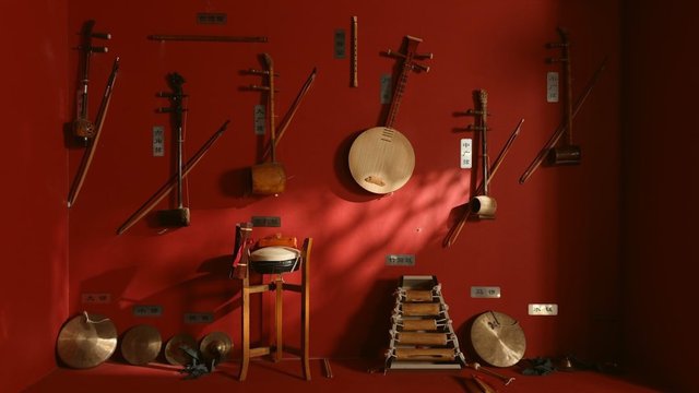 Traditional string and percussion instruments displayed on a red museum wall