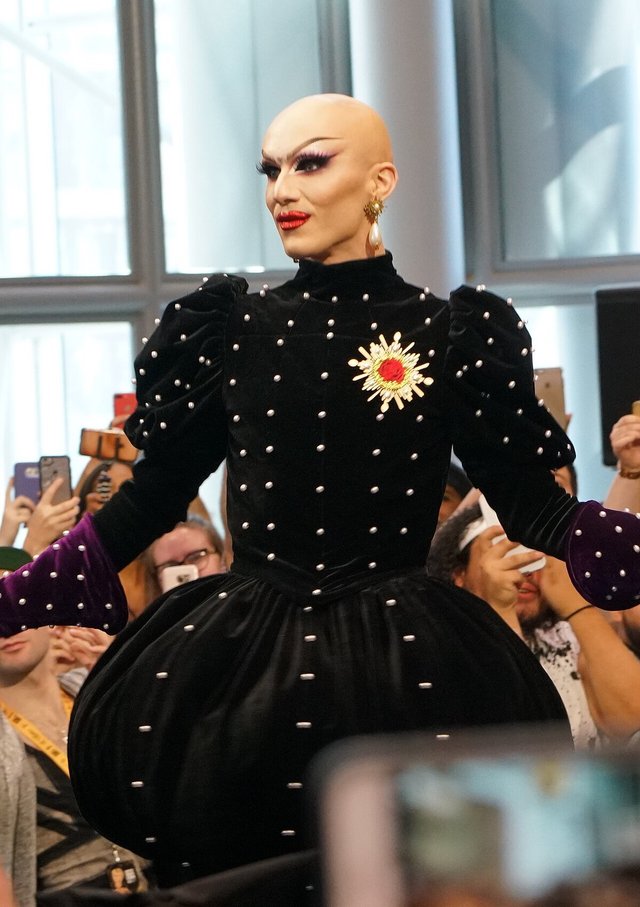 Sasha Velour in a black velvet gown studded with pearls, with a crowd holding up phones behind