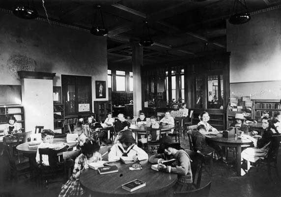 Historic 1913 photo of children reading at tables in a Los Angeles Public Library branch children's reading room