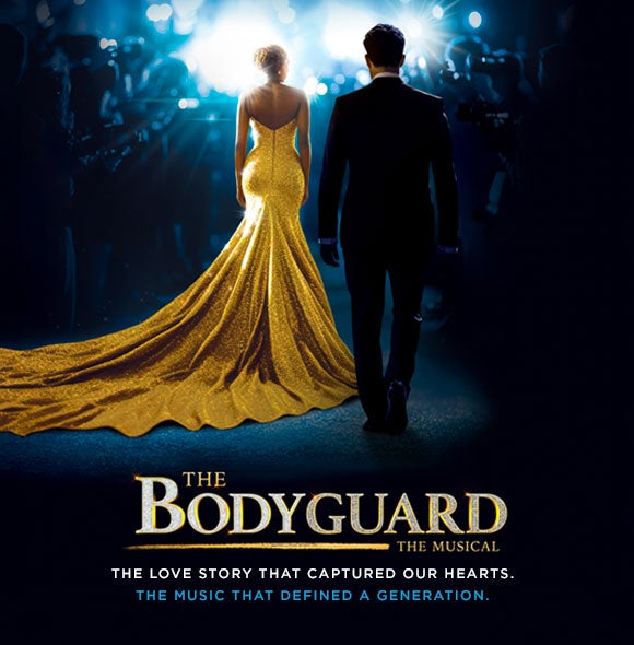 A woman in a long gold gown and a man in a dark suit walk away from the camera toward bright lights and photographers, with The Bodyguard title below