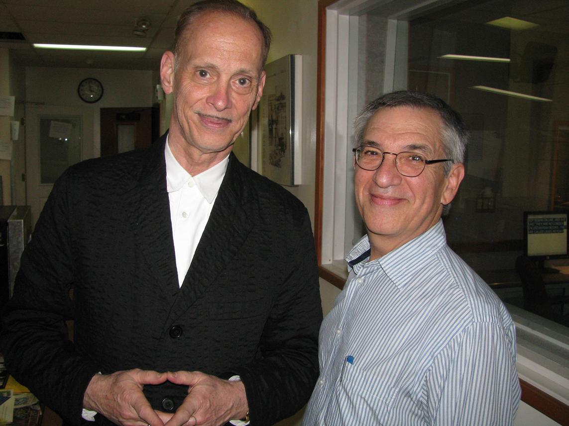 Film director and comedian John Waters standing beside historian Jon Wiener after a podcast taping