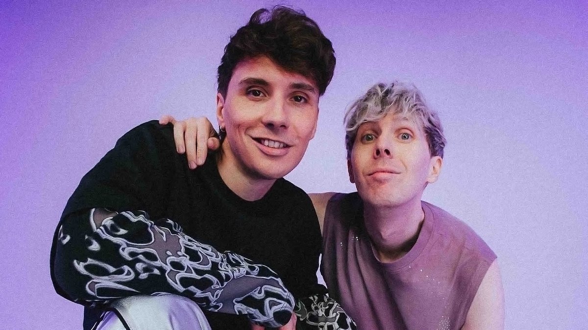 Dan Howell and Phil Lester posing together against a lavender backdrop