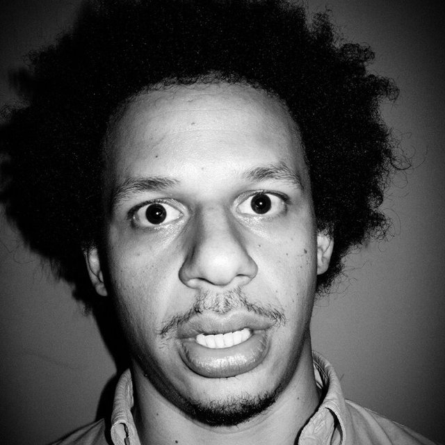 Black-and-white close-up portrait of comedian Eric Andre with wide eyes and a startled expression