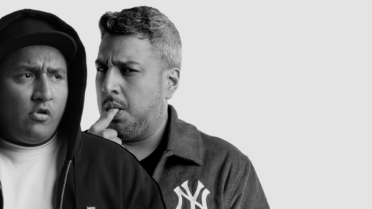 Black and white promo photo of Hablando Huevadas hosts Jorge Luna and Ricardo Mendoza, one in a dark hood and cap, the other in a corduroy jacket with a finger to his lip