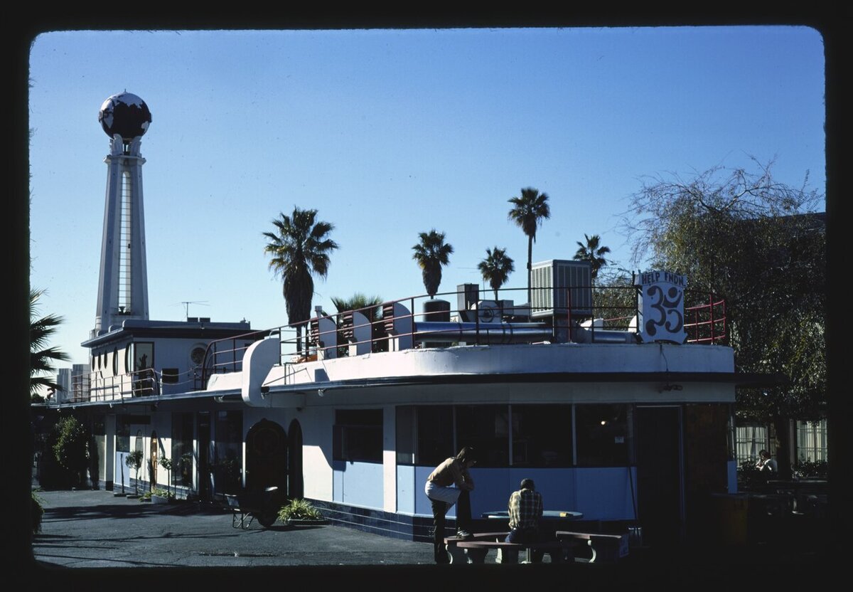 Streamline Moderne building with a globe-topped tower and palm trees under a blue sky on Sunset Boulevard in Hollywood