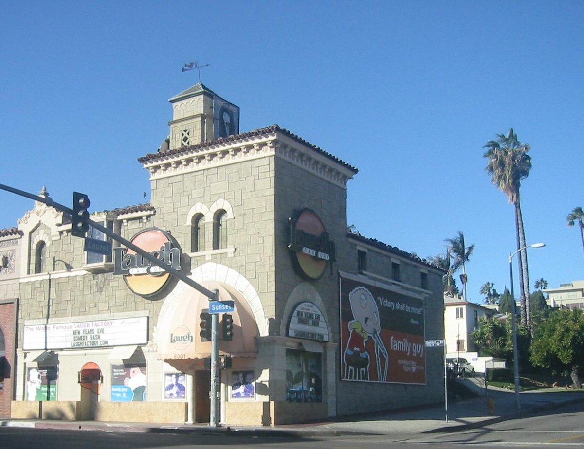 Exterior of the Laugh Factory comedy club on Sunset Boulevard in Hollywood, a stone building with a round logo sign