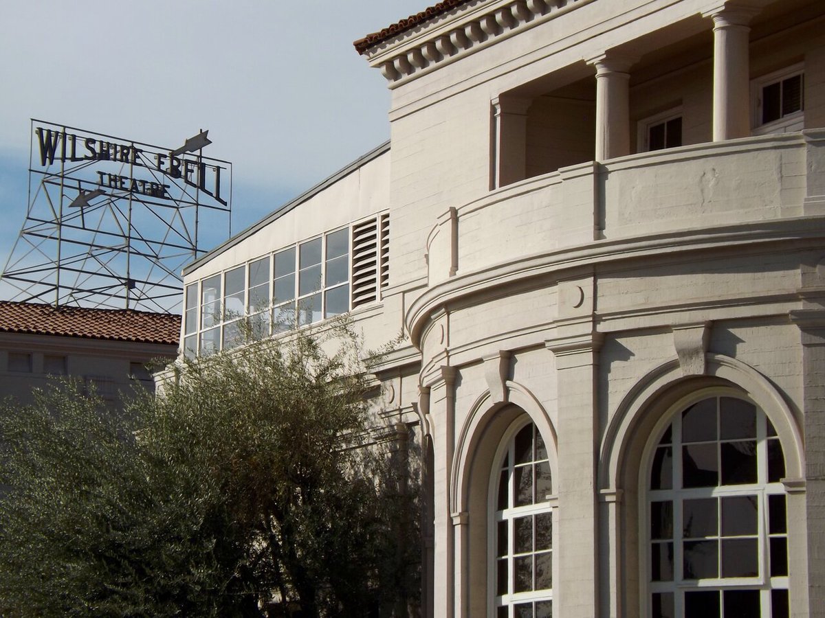 Exterior of the Wilshire Ebell Theatre in Los Angeles with a directional sign in the background