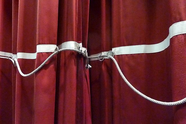 Close-up of deep red stage curtain folds with a white pulley rope across them