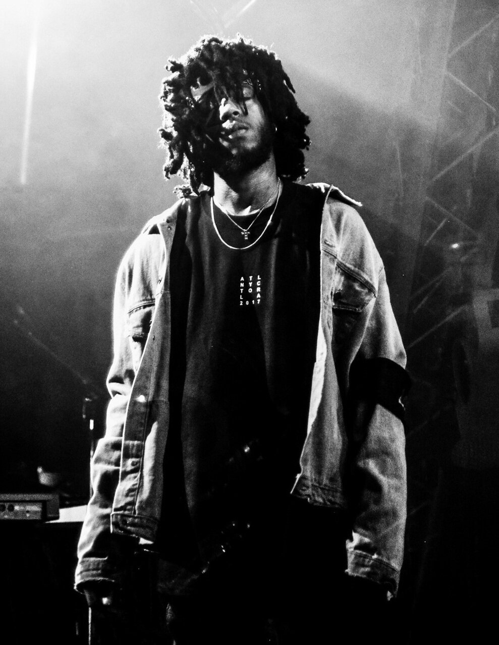 Black-and-white photo of 6LACK on stage in a denim jacket with hair falling over his face