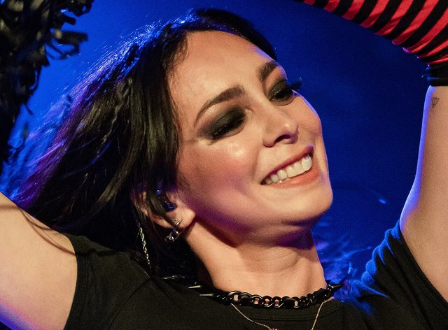 A smiling singer on stage with an arm raised under blue lighting