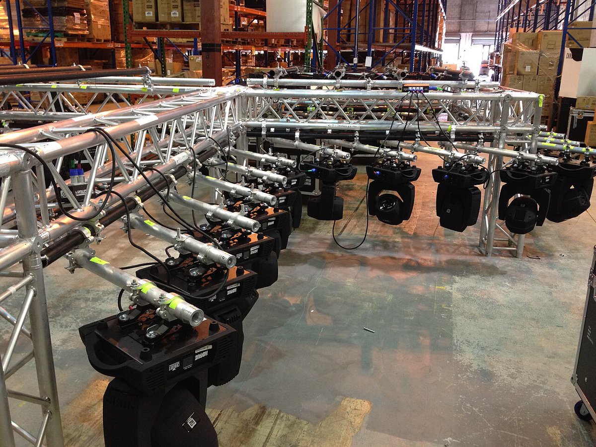 A rigging truss with a row of stage lights seen from below in a large hall