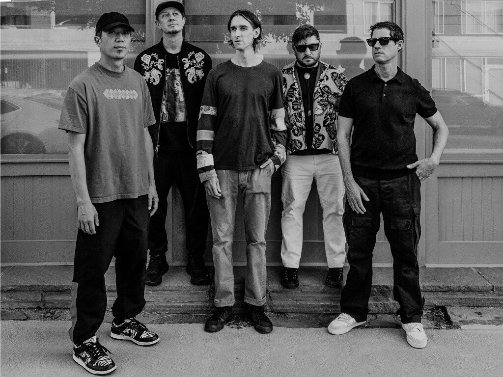 Black-and-white group portrait of five men standing in front of a storefront