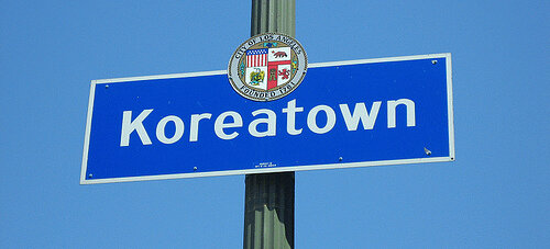 Blue Koreatown neighborhood street sign on a pole against a clear sky