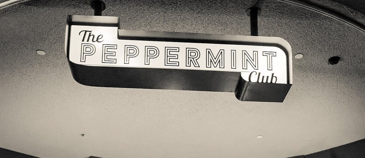 The illuminated Peppermint Club sign hanging over the club's stage