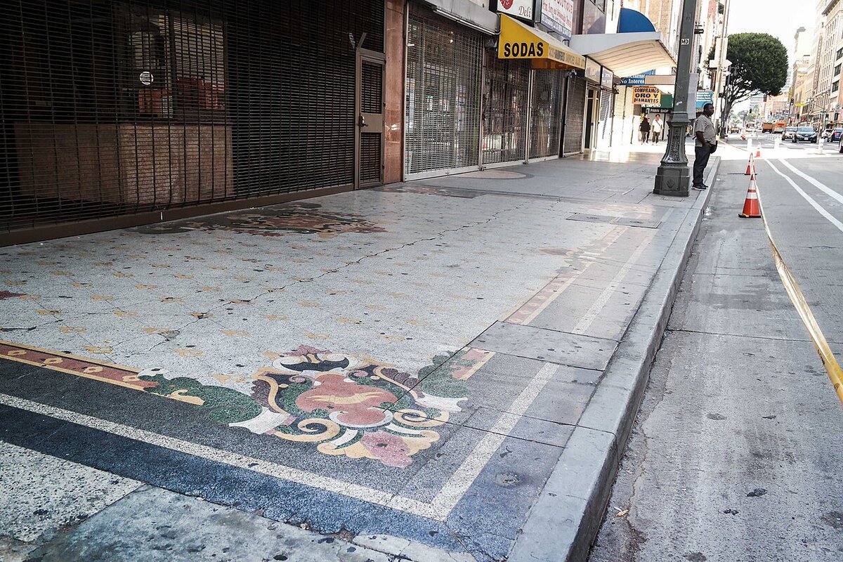 Ornate mosaic sidewalk in front of shuttered storefronts on a downtown Los Angeles theater district block