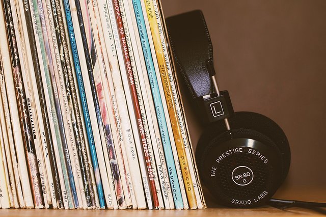 A row of vinyl record spines in a crate beside a pair of over-ear headphones