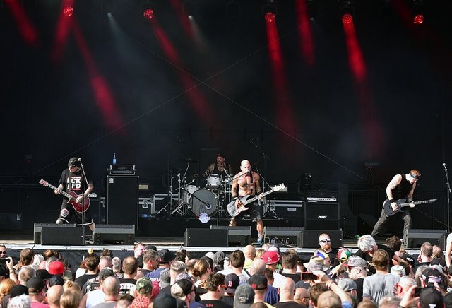 A hardcore band playing on a festival stage under red lights with a crowd in front