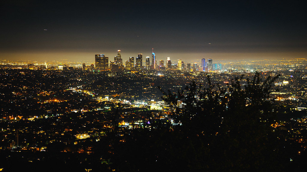 Downtown Los Angeles skyline glowing at night, seen from the hills across a sea of city lights