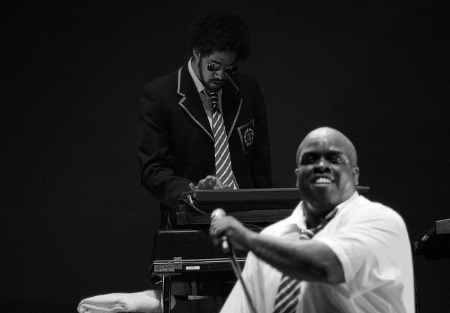 Black-and-white photo of two members of Gnarls Barkley on stage, one at a keyboard in a school blazer and one singing into a microphone