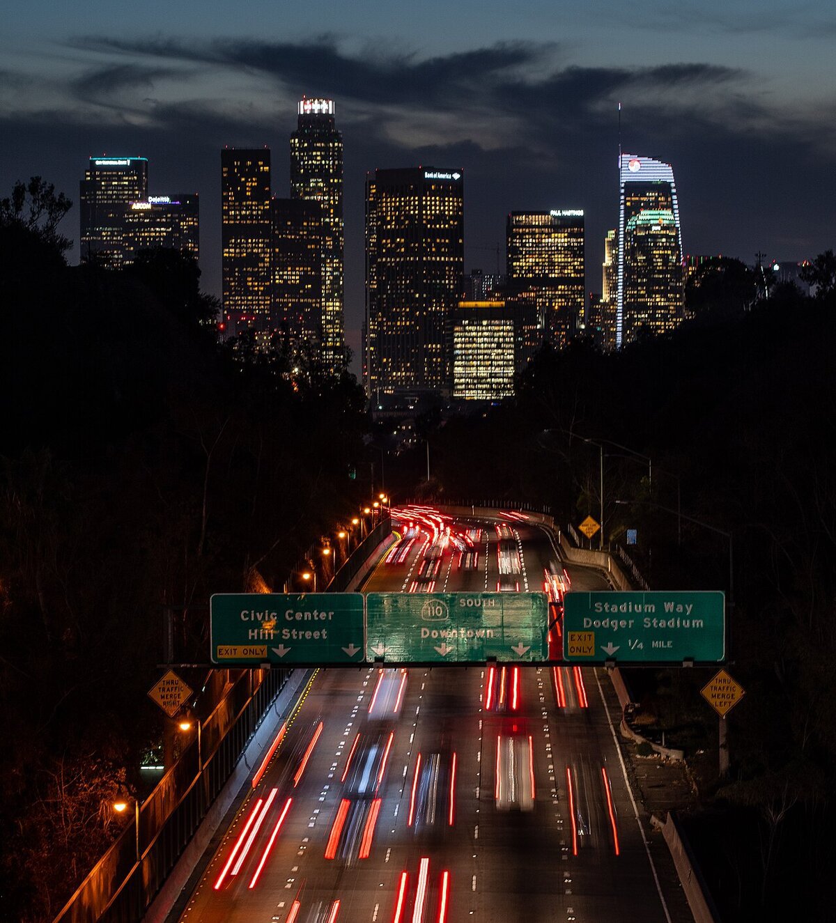 Downtown Los Angeles skyline at dusk above the 110 freeway with streaked taillights