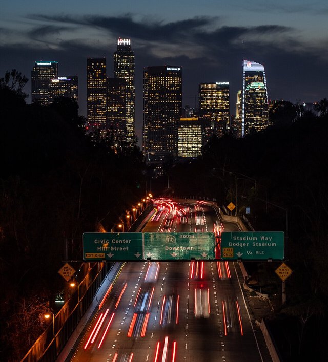 Downtown Los Angeles skyline at dusk above the 110 freeway with streaked taillights