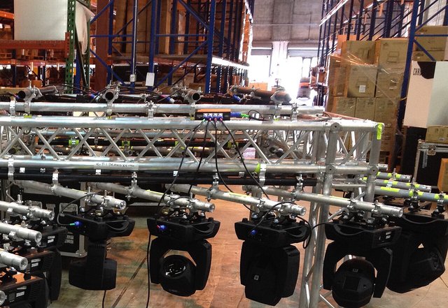 Overhead lighting trusses hung with rows of black stage lights in a warehouse hall