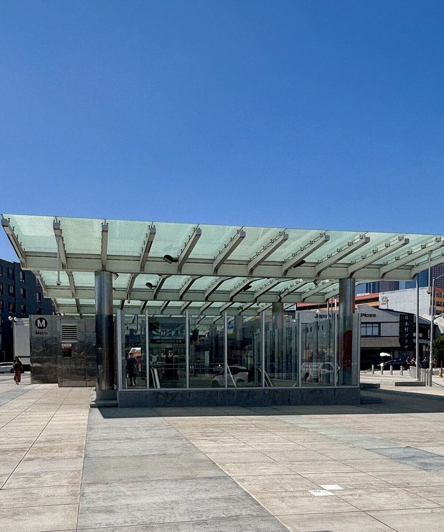 Glass-canopied Metro station entrance on a sunlit plaza in Little Tokyo, Los Angeles