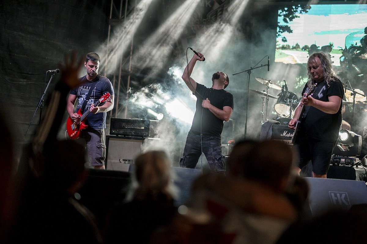 A band playing outdoors on a festival stage with white stage lights