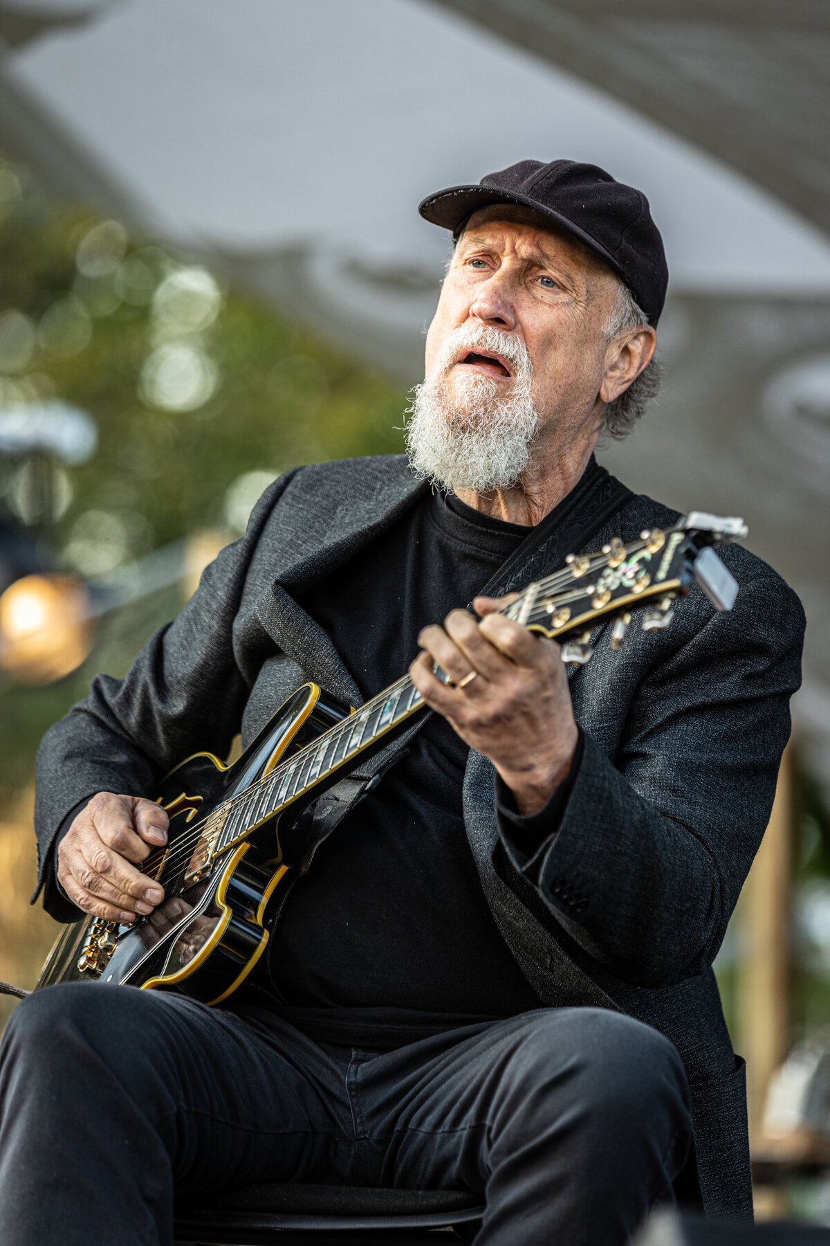John Scofield playing a hollow-body electric guitar on an outdoor stage