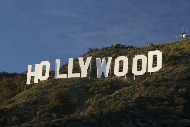 The white Hollywood sign on a green hillside under a deep blue evening sky